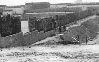 Fotografía en blanco y negro de las obras: muro de piedra y terraplén de tierra de las gradas.
